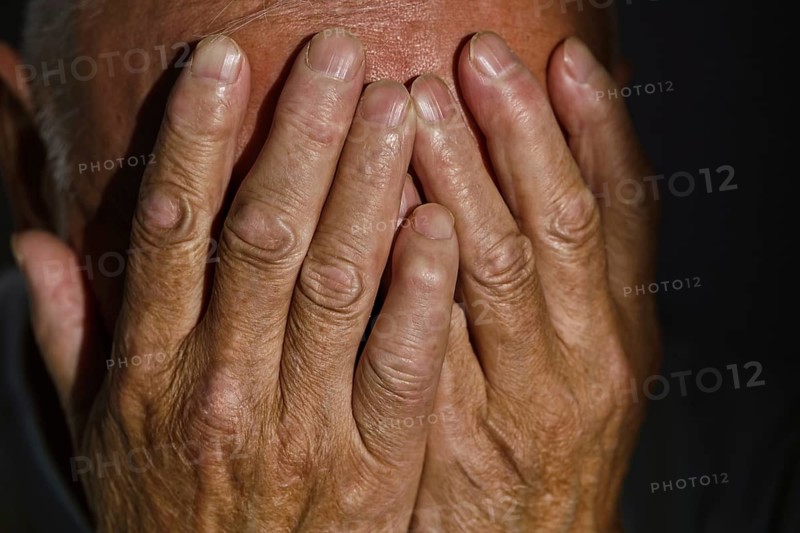 Close-up of a senior man's weathered hands gently covering his face, evoking emotions of contemplation and introspection Highlighting age's beauty and wisdom