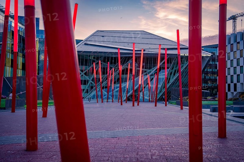 Modern architectural installation with red pillars at dusk in an urban square, Docklands Dublin, Ireland