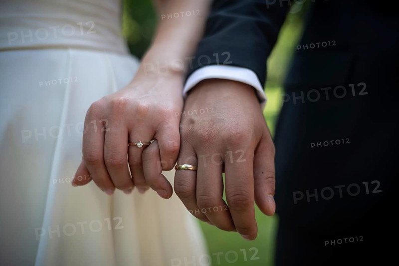 Close up of a bride and groom holding hands showing elegant gold wedding rings and a diamond engagement ring during a summer ceremony, Lubin in Poland