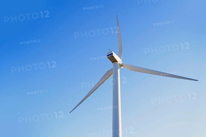 A towering wind turbine set against a vibrant blue sky in California, USA, showcasing renewable energy. The image highlights clean technology in a serene and natural setting