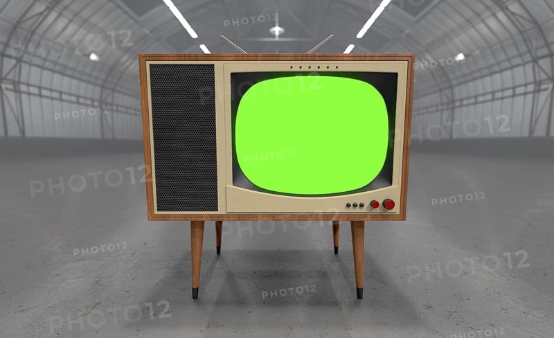 Vintage television with chroma green screen resting in the middle of an empty warehouse