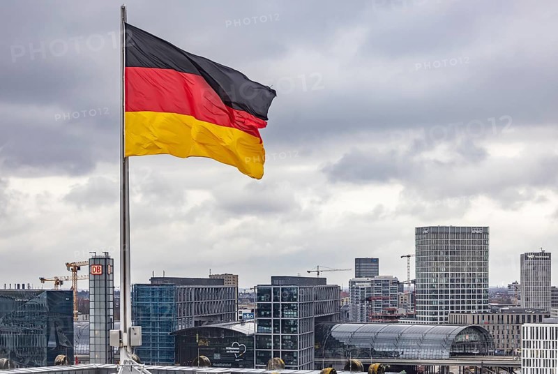 Reichstag building Berlin with German flag. Seat of the German Bundestag. Visitors in the dome on the roof of the building. View of the main train station. Berlin, Germany