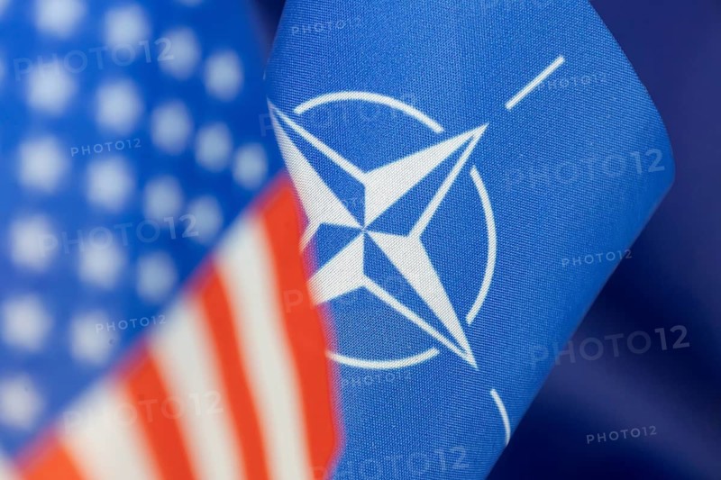 NATO flag, blurred in the foreground the US flag