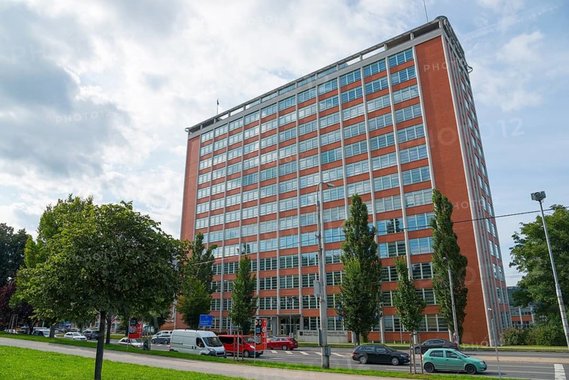 Large brick building in an urban environment with passing cars and trees on a cloudy day, Batuv mrakodrap, Batas skyscraper, Zlín, Zlin, Zlínský kraj, Moravia, Czech Republic