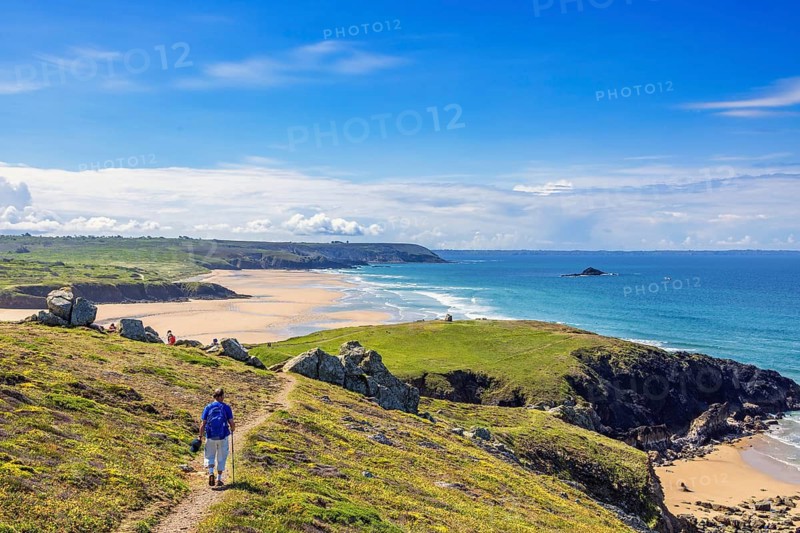 Man walking on a hiking trail on the French coast with a beautiful view of the sea on a sunny summer day, Crozon peninsula, Pointe de Lostmarc'h, Bretagne, France