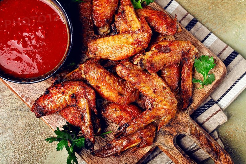 Fried in the oven, chicken wings, with spices, tomato sauce, on a cutting board, gray background, no people, homemade