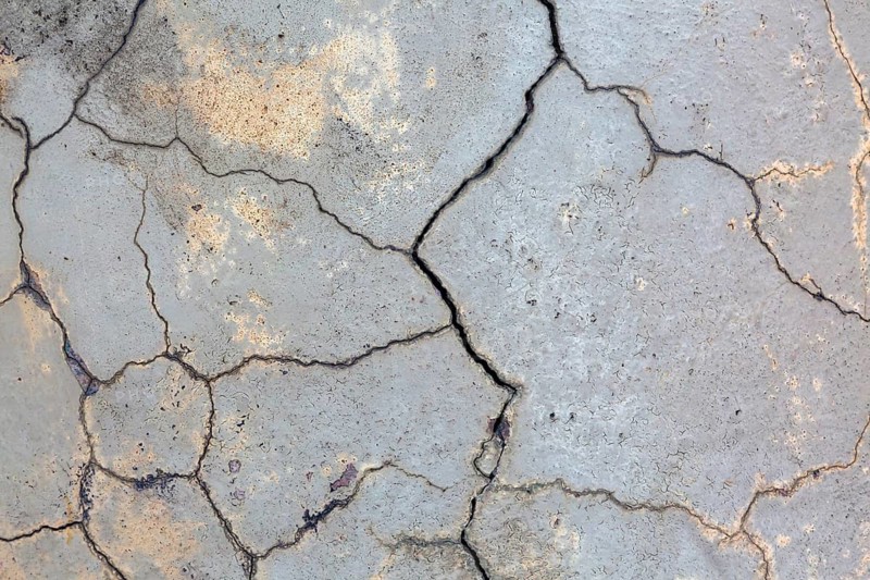 Close-up of multiple small cracks and deep fissures on grey painted concrete foundation exterior house wall in poor condition, Quebec, Canada