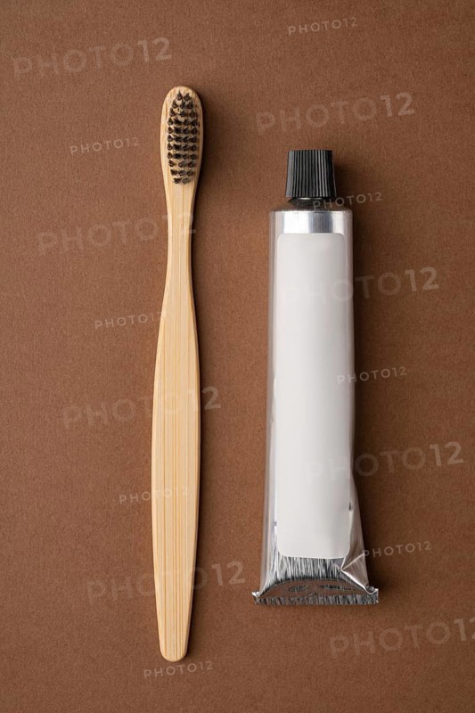 Top view of a bamboo toothbrush and a toothpaste tube on a brown paper background. The image highlights eco-friendly dental care products with a focus on sustainability