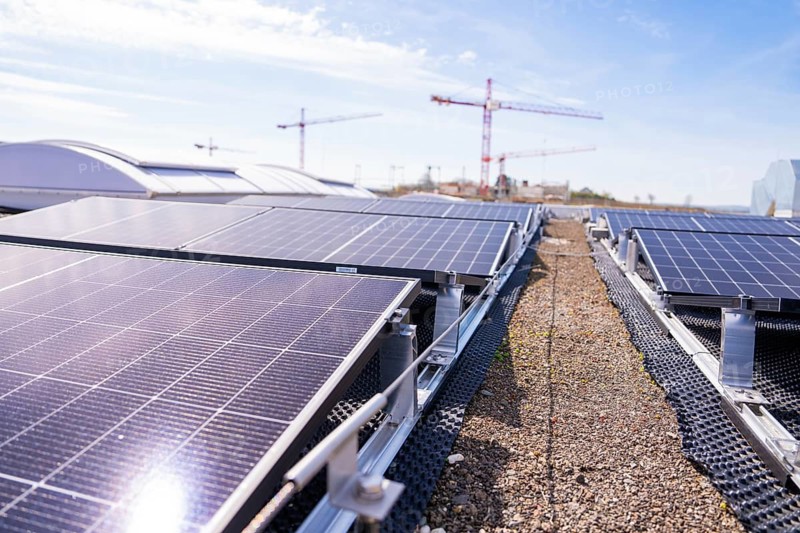 Solar panels on a roof near cranes in sunny skies, PV installation. OBI Baumarkt, Mühlacker, Enzkreis, Germany