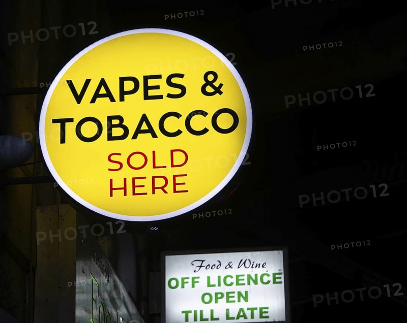 Sign for Vapes and Tobacco Sold Here outside shop dark at night, London, England, UK