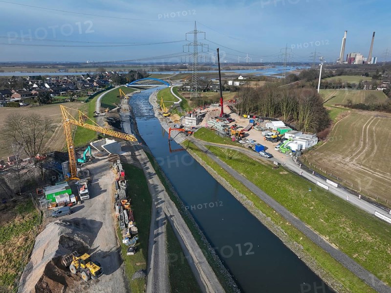 Dinslaken, Voerde, North Rhine-Westphalia, Germany - New Emscher estuary into the Rhine. New construction of the railway bridge and restoration of the dykes after dyke erosion during the 2023 flood. Renaturalisation of the Emscher. Flood protection through land expansion. In the background, the decommissioned STEAG Voerde coal-fired power plant. The mouth of the Emscher into the Rhine was moved almost 500 metres north from Dinslaken to Voerde. Fish can now swim barrier-free up the new Emscher from the Rhine through a newly created floodplain area. Following the construction of a parallel sewer, the Emscher has been completely free of sewage since January 2022. The river was previously an open, above-ground combined sewer with rainwater and wastewater
