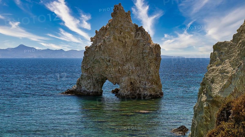 An impressive rock with a hole jutting out of the sea under a lively sky, Aspragremna, White Cliffs, Mavorspilia Beach, Kimolos Island, Kimolos, Cyclades, Greek Islands, Greece