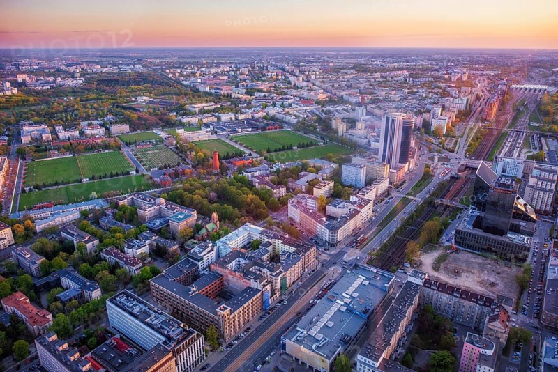 Broad view across the Warsaw skyline in Poland with skyscrapers, cityscape layers, warm roof patterns, sunset color and dramatic sky