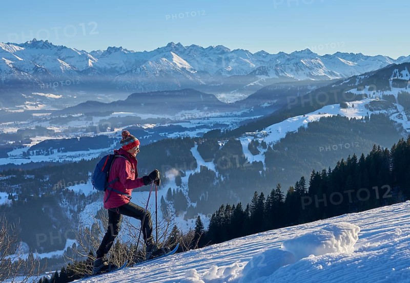 Nice and active senior woman snowshoeing in in the snow covered Allgaue alps above the valley of river Iller, Immenstadt, Bavaria, Germany