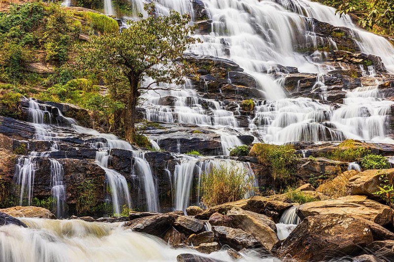 Mae Ya waterfall with cascading flowing water surrounded by lush tropical vegetation, near Doi Inthanon National Park, Chiang Mai Province, Thailand