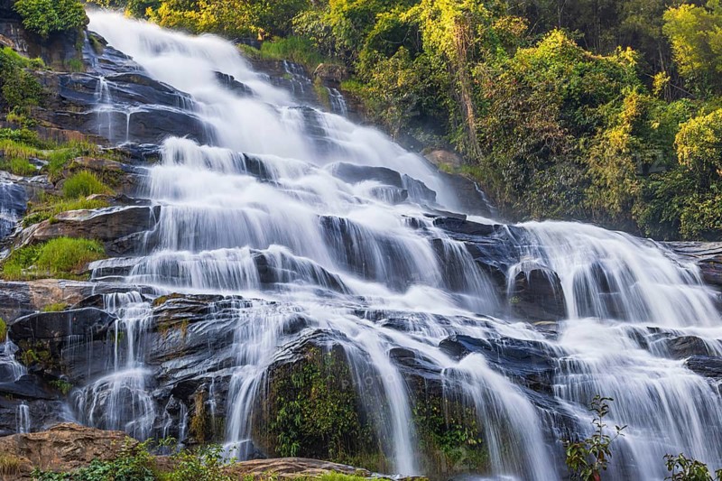 Mae Ya waterfall with cascading flowing water surrounded by lush tropical vegetation, near Doi Inthanon National Park, Chiang Mai Province, Thailand