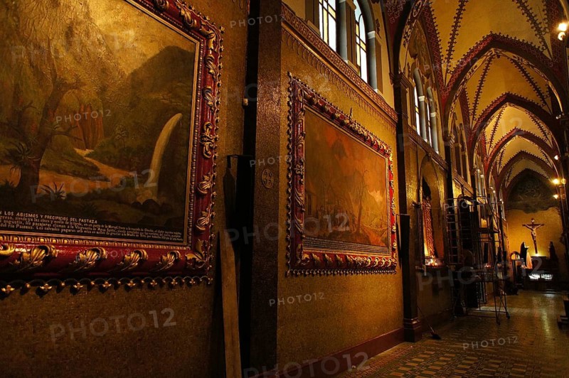 Interior of a Gothic-style church with decorated paintings and warm lighting, Cuenca, Ecuador