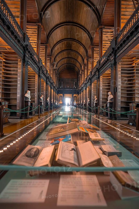 Historical library with exhibited books in a glass case and busts, Trinity Collage, Dublin, Ireland