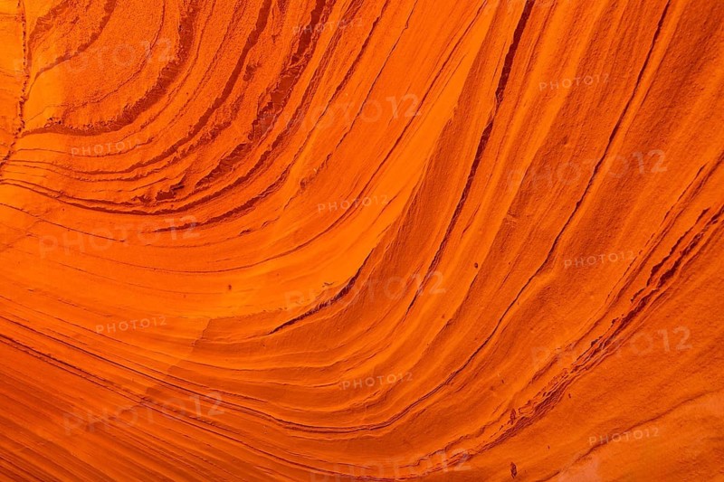 Biidi the arch cave in page, arizona, showcasing vibrant orange sandstone layers and intricate striations that reveal erosion, sedimentation and desert geology over time