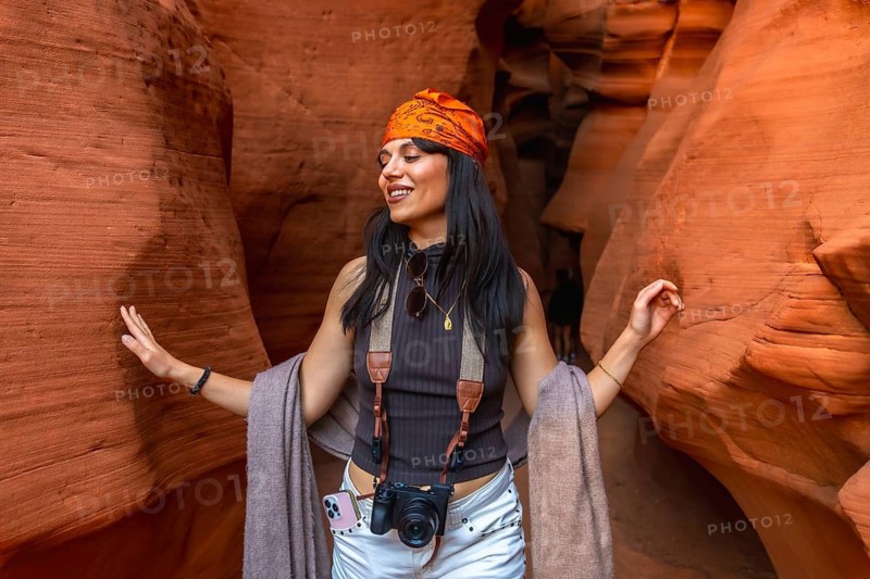 Woman joyfully experiencing the iconic sandstone walls of antelope canyon, touching the sculpted rock while hiking during a travel adventure in page, arizona, united states