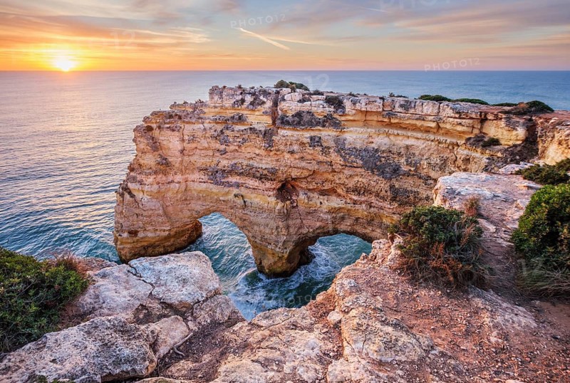 Sunrise view of Praia da Marinha beach in Algarve, Portugal, with golden cliffs, sea stacks, Atlantic waves, turquoise water, and a rocky cove