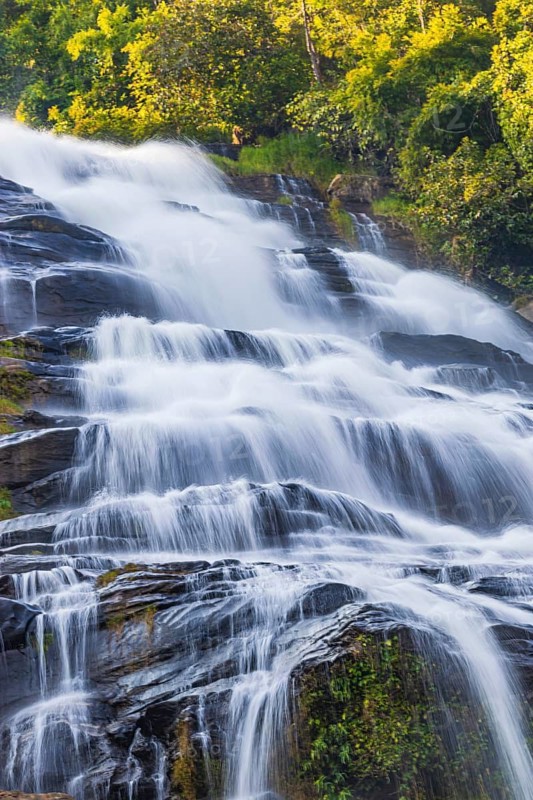 Mae Ya waterfall with cascading flowing water surrounded by lush tropical vegetation, near Doi Inthanon National Park, Chiang Mai Province, Thailand