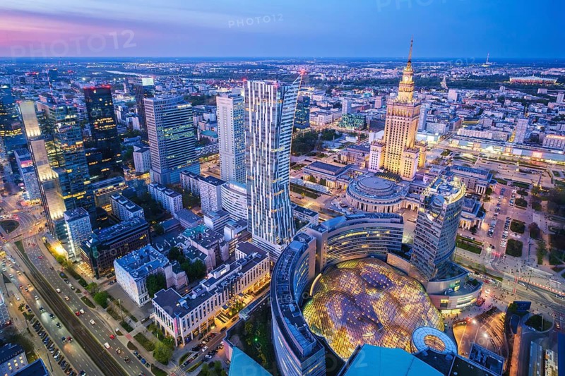 Wide city view over Warsaw, Poland, with the Palace of Culture landmark, skyline, evening glow, blue hour twilight and city lights