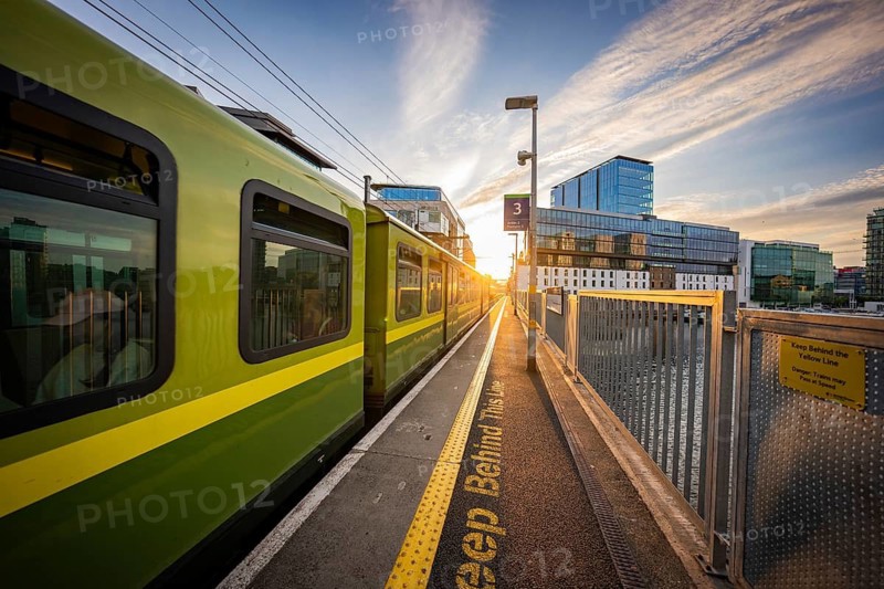 A train on the platform at sunset with modern buildings in the background, Dockland Dublin, Ireland