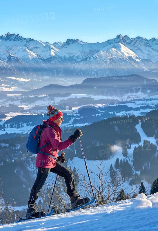 Sportive senior woman hiking with snow shoes in the snowy Allgaeu Alps above Lake Alosee, Immenstadt, Bavria, Germany