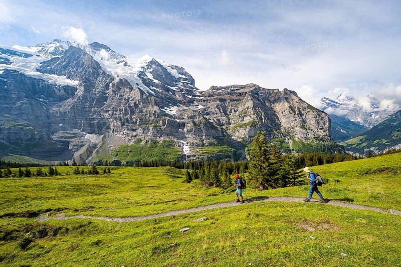 Two hikers on a hiking trail on Mettlenalp, mountain panorama with peaks Mönch and Jungfrau, Bernese Alps, Bernese Oberland, Switzerland