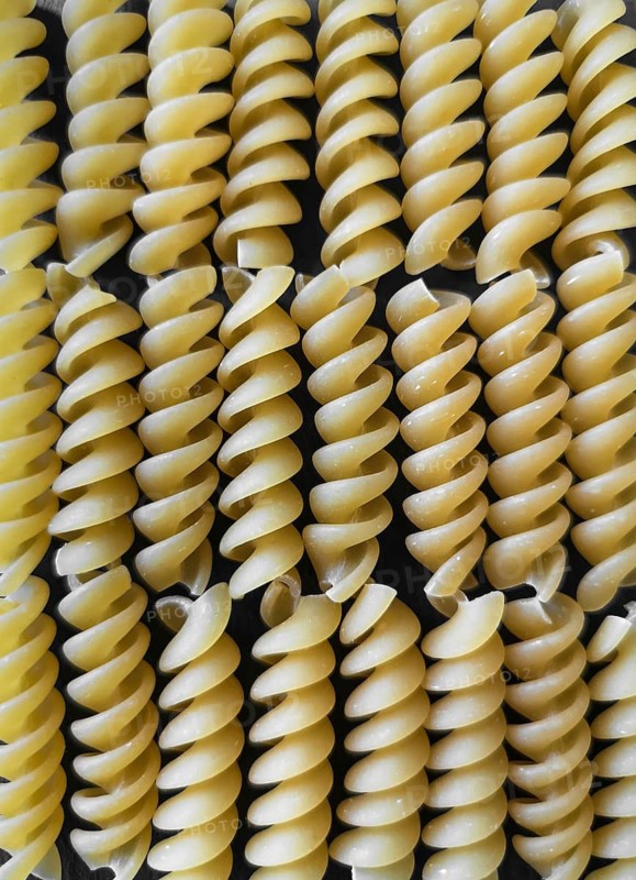 The texture of fusilli pasta on a black background. wallpaper. background. Close-up. Vertical