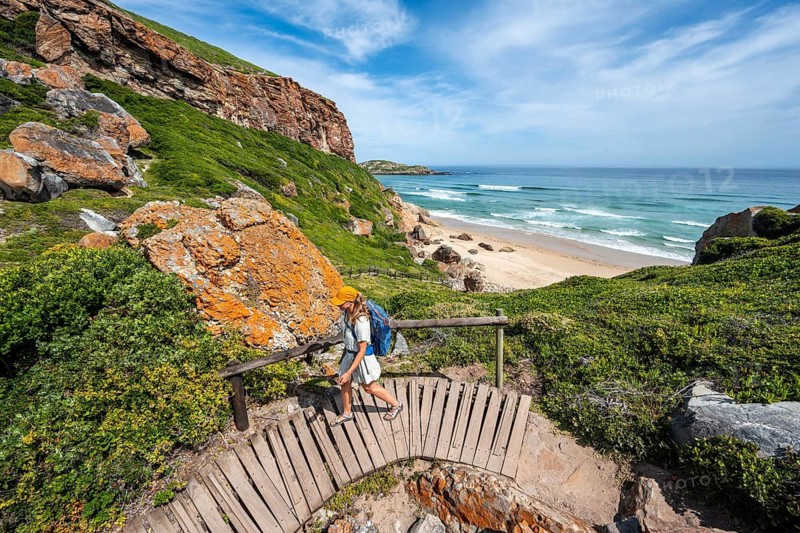 Young pretty woman wearing dress off coast and sea at Robberg Nature Reserve, Plettenberg Bay, South Africa