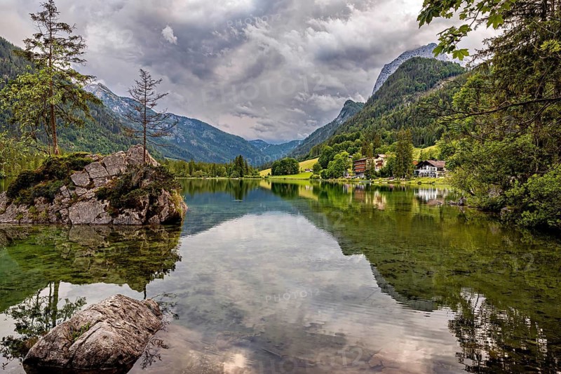 Mountain lake with crystal clear water, reflecting surroundings and surrounded by alpine idyll, The Hintersee near Berchtesgaden in Bavaria