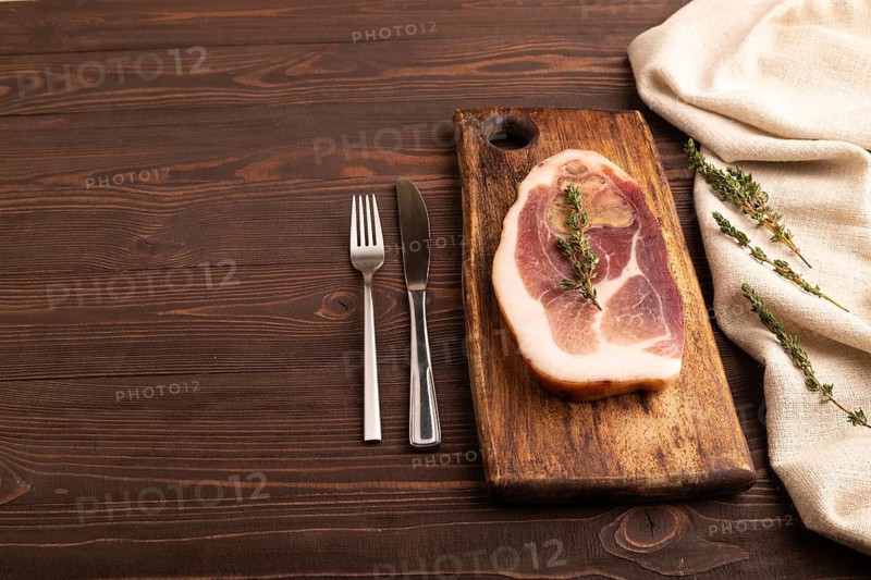 Dry-aged steak, Pork ham with thyme on brown wooden background and linen textile. side view, copy space