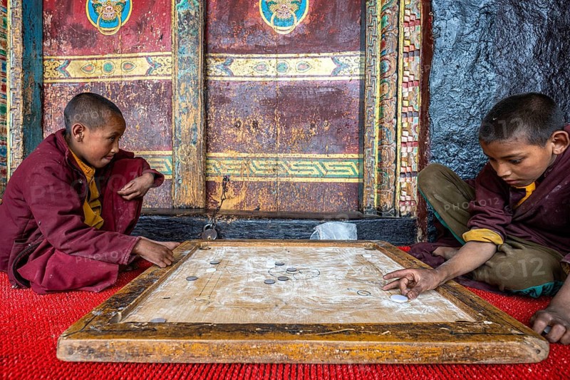 Two young Buddhist monks, novices playing carrom, skill game, finger billiards, Buddhist monastery, Gompa, Humla region. West Nepal, Nepal