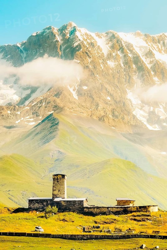 Aerial view Lamaria Monastery with snow-covered Shkhara peak - highest mountain in Georgia.Famous summer travel destination in caucasus. Ushguli village is UNESCO World Heritage Site. Svaneti tours