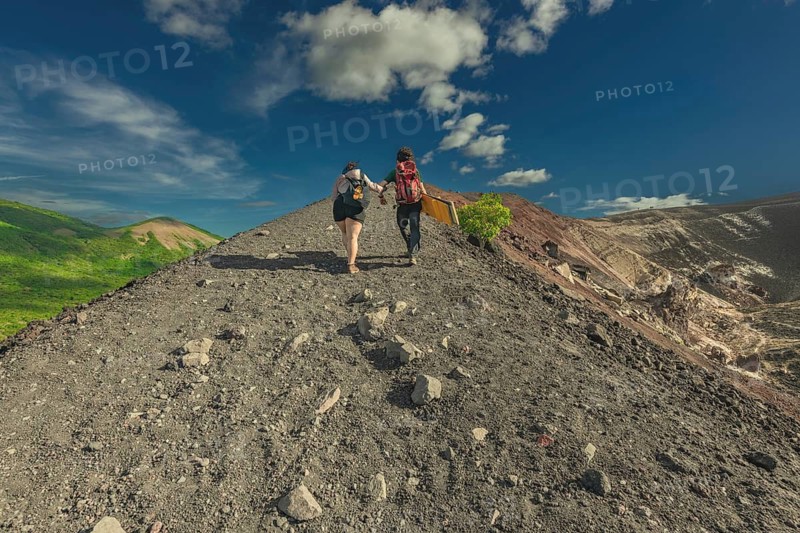 Landscape of tourists hiking to the summit of Cerro Negro volcano. Rear view of two tourists climbing Cerro Negro with a beautiful landscape in the background