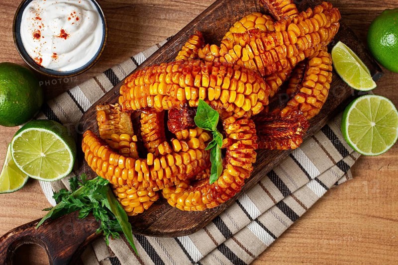 Corn ribs, with cream sauce, spices and lime, appetizer, on a wooden cutting board, homemade, no people