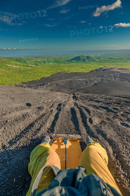 View of a person on Cerro Negro riding a sandboard. Person sandboarding on Cerro Negro, Nicaragua