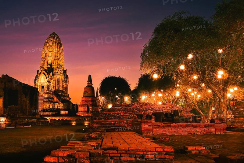 Wat Ratchaburana ancient temple in Ayutthaya Historical Park, Thailand .Towering central prang and crumbling brick ruins illuminated by warm golden lights against dark night blue hour sky