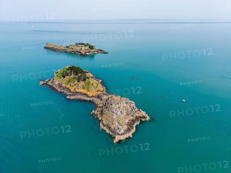 Aerial view of a small chain of islands in the turquoise sea off the coast of the municipality of Cancale. You can see the fortified Île des Rimains and the neighboring rocky islands on the Côte d'Émeraude, Emerald Coast, Ille-et-Vilaine department, Brittany, English Channel, France