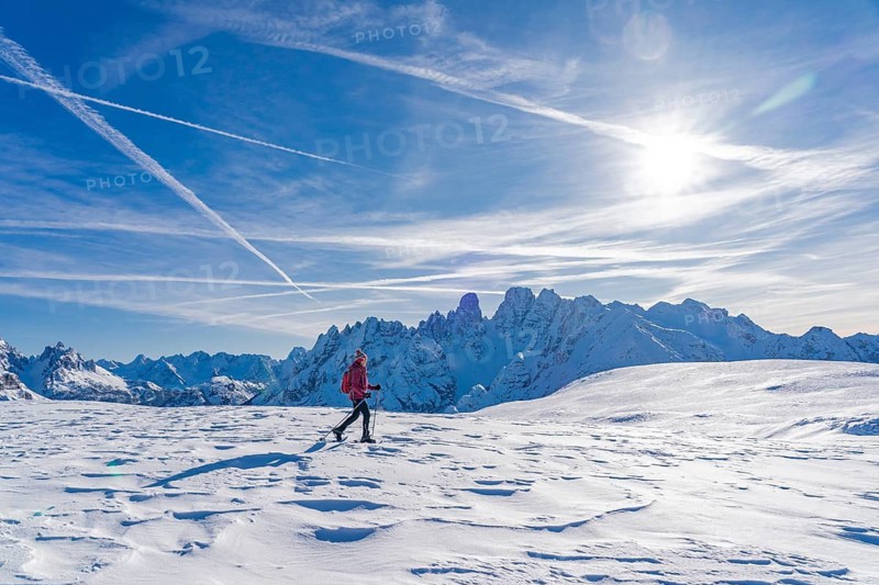 Active senior woman hiking in winter with snow shoes under the famous Cristallo summit, Dolomites, Toblach, South Tyrol, Italy