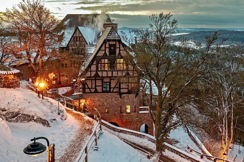 Timbered house in evening lighting, surrounded by snow-covered paths and trees at dusk, The Hotel an der Wartburg near Eisenach in Thuringia