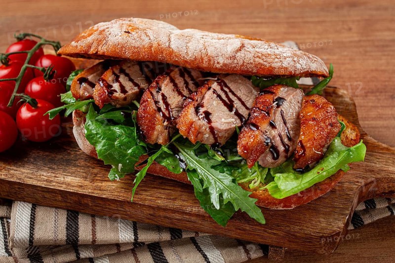 Sandwich with duck breast and arugula, balsamic sauce, on a wooden chopping board, breakfast, homemade, without people