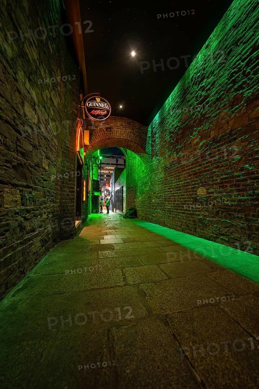 A quiet alley bathed in green light, with stone walls and a mysterious atmosphere, nightlife, Dublin, Ireland