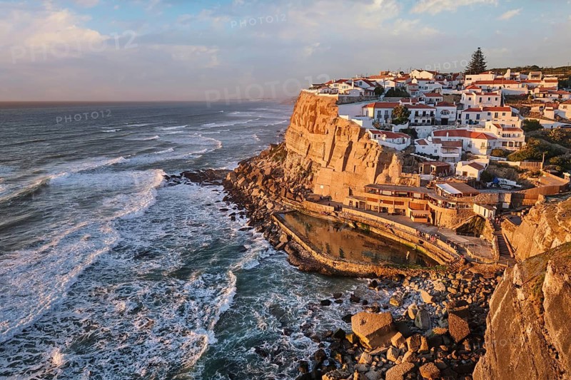 Azenhas do Mar with its stunning seaside charm as sunlight casts warm tones over the cliffs and ocean. Portugal