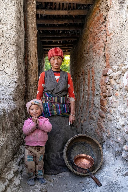 Friendly young woman in traditional dress with toddler in a covered doorway, Tangge, Mustang, Upper Mustang, former kingdom, Himalayas, Nepal