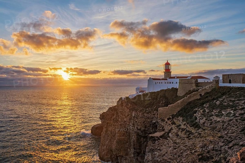 View of the Lighthouse of Cabo de Sao Vicente in Sagres, Algarve, Portugal, at sunset with rocky headland and Atlantic ocean