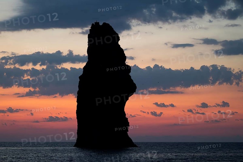 Silhouette of a towering monumental rock pin after sunset, near Filicudi, Aeolian or Lipari Islands, southern Italy, Italy