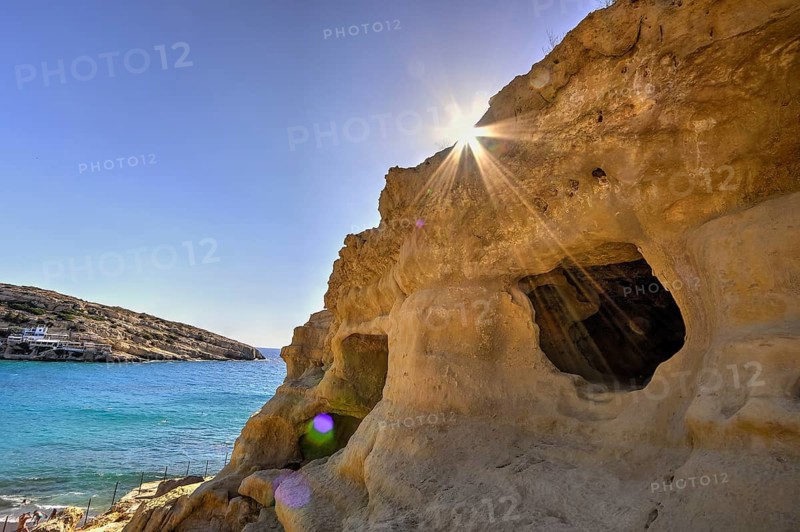 Neolithic caves, former hippie paradise, sun rays break through rocks and illuminate a cave by the sea, Matala, south coast, Crete, Greek Islands, Greece